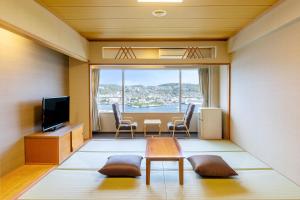 a room with a table and chairs and a television at Ooedo Onsen Monogatari Premium Nagasaki Hotel Seifu in Nagasaki