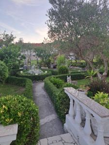 a garden with a stone bench and bushes and trees at Sweet home in Rab +8 photos