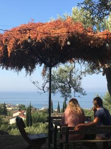 two people sitting on a bench under an umbrella at Camping Himara in Himare