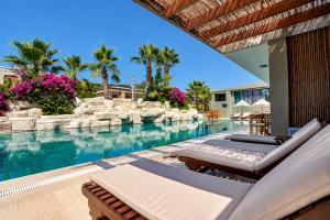 a swimming pool with chaise lounges next to a resort at Sarum Çeşme in Çeşme