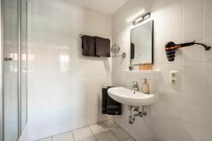 a white bathroom with a sink and a shower at Königslinde am Tegernsee in Bad Wiessee
