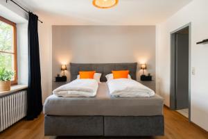 a bedroom with a gray bed with orange pillows at Königslinde am Tegernsee in Bad Wiessee