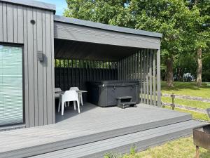 a wooden deck with a grill and a table and chairs at Sauna & stay in Engure