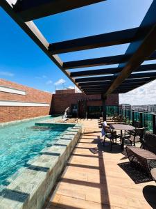 a pool on top of a building with a table and chairs at Wish Residence Ap 710 in Maceió