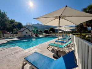 a group of chairs and an umbrella next to a swimming pool at Camping Familial - Parc Aquatique - Grande Aire de Jeux à la Montagne in Agos-Vidalos