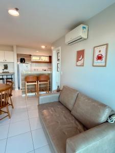 a living room with a couch and a kitchen at Mandai Apartamentos in Cabo Frio