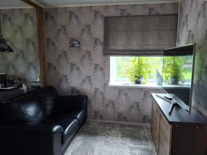a living room with a leather couch and a window at Korter kesklinna piirkonnas in Tartu +1 photo