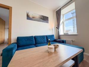 a living room with a blue couch and a table at Cozy Apartment Kaija in Liepāja