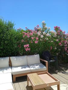 a couch and a coffee table on a deck with pink flowers at Iris in Valras-Plage