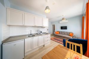 a kitchen with white cabinets and a living room at Mavi Kıyı Suites in Kaş