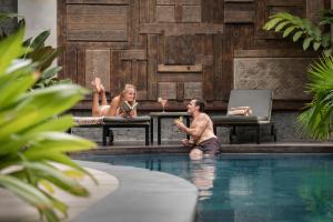 un hombre y dos mujeres sentados en una piscina en Akana Boutique Hotel, en Sanur