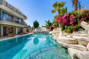 a swimming pool in front of a building with flowers at Sarum Çeşme in Çeşme