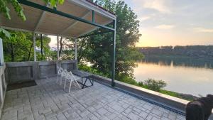 a porch with a bench and a view of a lake at VRHouse Vorbis River House in Ada Skeljanska