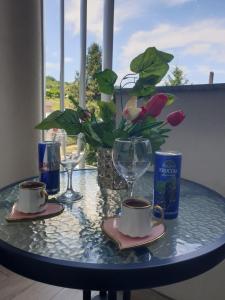 a table with two cups and glasses and a plant at Elly in Modriča