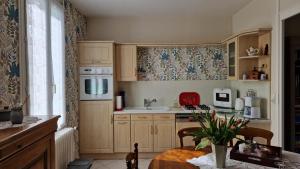 a kitchen with wooden cabinets and a table and a sink at Gîte à 15km PUY duFOU 5pers 3chambres in Pouzauges +6 photos