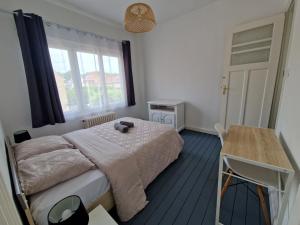 a bedroom with a bed and a table and a window at Spacieux duplex familial proche Dunkerque et plage in Coudekerque-Branche