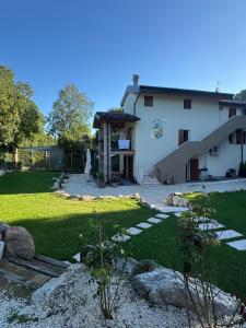 a large white house with a yard with green grass at Casa dei Colli in Monzambano