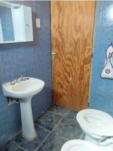 a bathroom with a sink and a toilet and a door at Hostel Portal del Sol in Fiambalá +5 photos
