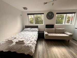 a bedroom with a bed and a couch and two windows at The Lofton A Loft Above the Rest in Headingley