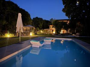 a swimming pool with an umbrella next to a house at Casa dei Colli in Monzambano