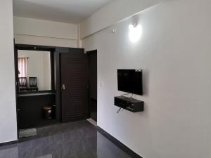 a room with a flat screen tv on a white wall at Hotel Gateway Inn in Kushālnagar