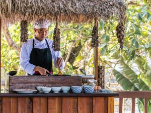 uno chef che prepara il cibo su un tavolo con ciotole di Riverside Boutique Resort, Vang Vieng a Vang Vieng