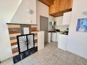 a kitchen with white cabinets and a tile fireplace at Nádaspart Vendégház in Zánka