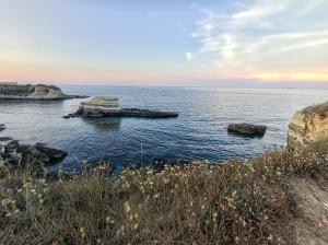 a view of the ocean with rocks in the water at Masseria Santa Laria in Borgagne +2 photos