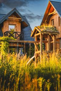 a wooden house with tall grass in front of it at Bieszczadzka Hawira - Domki w Centrum przy Jeziorze z Widokiem dla Rodzin in Polańczyk