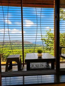 a table and a bench in front of a large window at Garbat valley view Matheran in Matheran