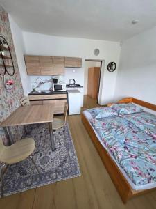 a bedroom with a bed and a table and a kitchen at Salem apartmany in Radava