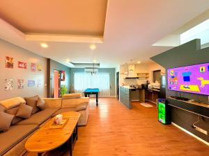 a living room with a couch and a table and a tv at A1-Mountain View Private Pool Villa-บางแสน in Chon Buri