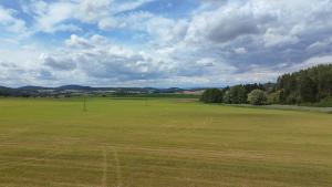a large green field with trees in the distance at Samoobslužná maringotka in Žihobce +8 photos
