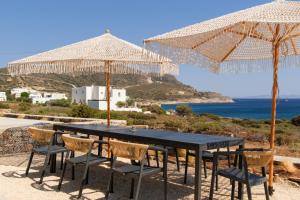 a table and chairs with umbrellas and the ocean at Antiparos Gems - The villa in Antiparos
