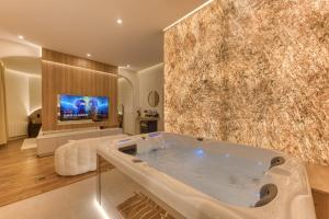 a large bathroom with a tub and a tv at Suite Prestige Spa Privatif D'exception in LʼIsle-Adam