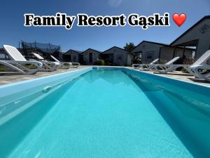 a swimming pool with chaise lounges and chairs in a house at Family Resort Gąski in Gąski