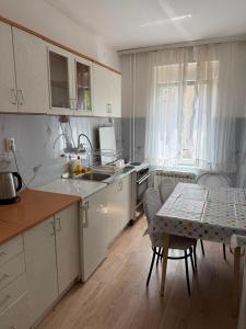a kitchen with white cabinets and a table and a table and chairs at Apartment Gajic in Belgrade