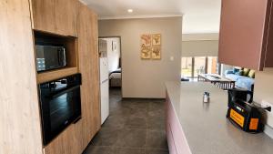 a kitchen with a microwave and a living room at Lloyds - unit 10 in Ermelo +3 photos