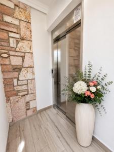 a vase filled with flowers sitting in front of a door at Vasiliu Boutique Hotel Ksamil in Ksamil