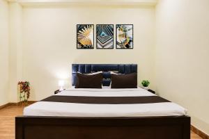 a bedroom with a large bed with three paintings on the wall at Rudraksh Residency in Varanasi