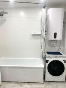 a white kitchen with a stove and a microwave at Квартира Иртыш in Pavlodar