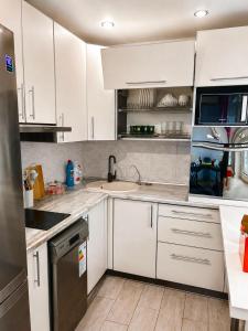 a kitchen with white cabinets and a sink at Квартира Иртыш in Pavlodar