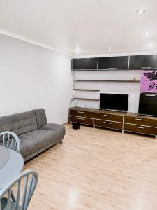 a living room with a couch and a flat screen tv at Квартира Иртыш in Pavlodar