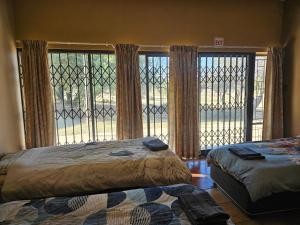 a bedroom with two beds and a large window at Tambuki Backpackers & Self-catering - Dinokeng in Hammanskraal