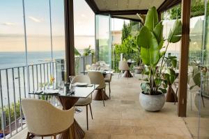a restaurant with tables and chairs and a view of the ocean at Hotel Metropole Taormina in Taormina