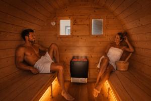 a man and a woman sitting in a sauna at Family Resort Gąski in Gąski