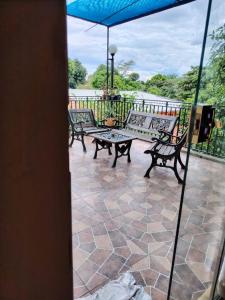 a patio with benches and a table and an umbrella at Mi Hábitat Lambaré - Habitaciones con Baño Privado, Cocina y Comedor equipados con electrodomésticos, con Quincho al Aire Libre in Asunción