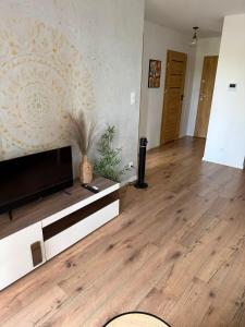 a living room with a television and a wooden floor at Apartament Leśna Mandala in Augustów +3 photos