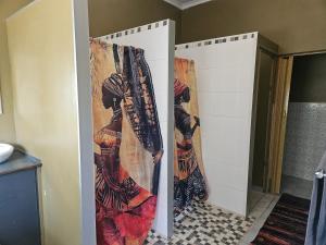 a bathroom with two stalls with curtains on them at Tambuki Backpackers & Self-catering - Dinokeng in Hammanskraal +8 photos