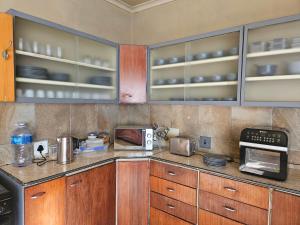 a kitchen with wooden cabinets and a microwave at Tambuki Backpackers & Self-catering - Dinokeng in Hammanskraal